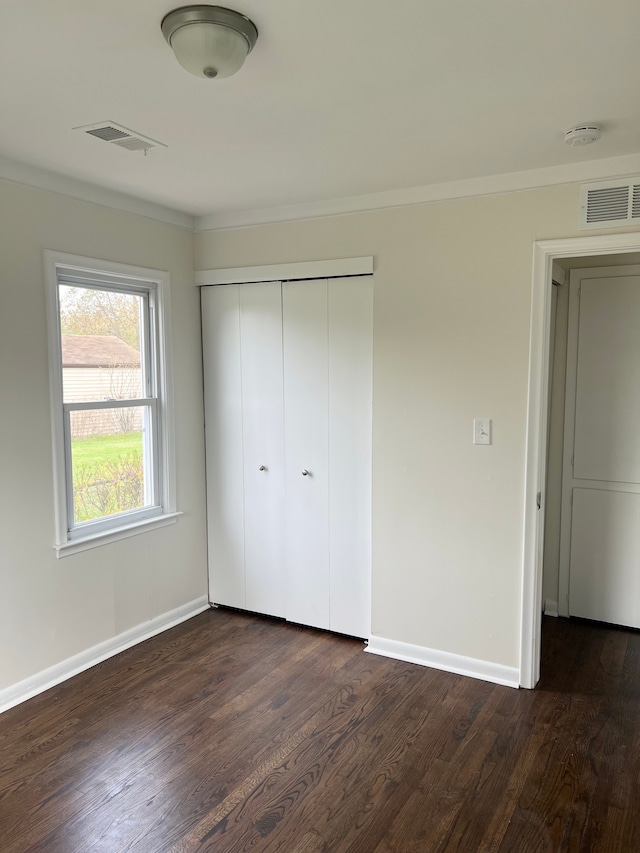 11389 Hupp Ave, Warren, MI 48089 - unfurnished bedroom featuring dark wood-style flooring, baseboards, ornamental molding, and a closet