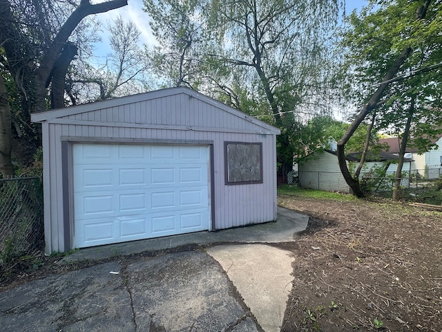 detached garage featuring fence and driveway