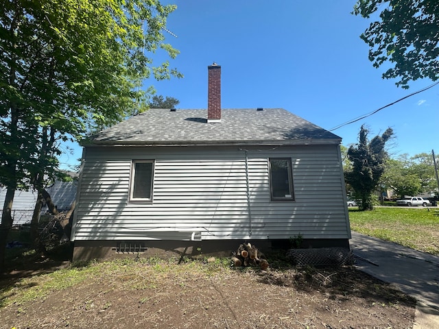 view of home's exterior with crawl space and a shingled roof