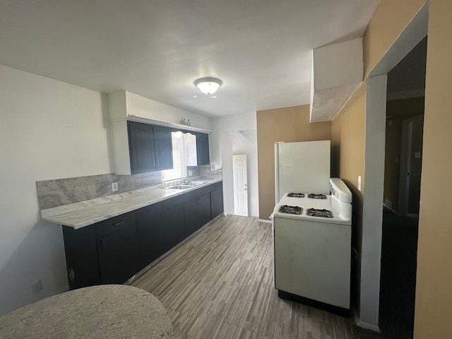 kitchen with range, a sink, light wood finished floors, light countertops, and freestanding refrigerator