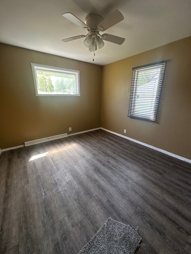 empty room with a baseboard heating unit, a ceiling fan, dark wood-type flooring, and baseboards