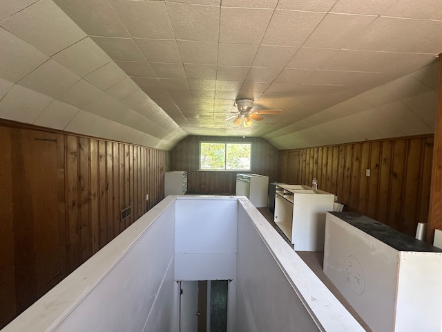 bonus room featuring wood walls, lofted ceiling, and a ceiling fan