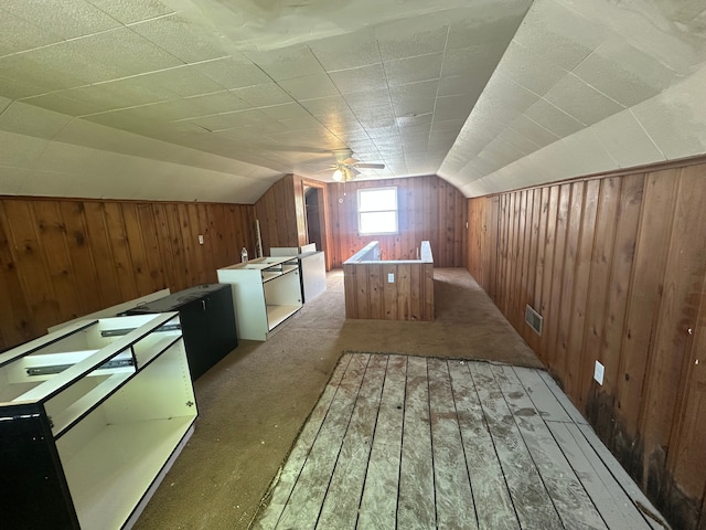 bonus room featuring wood walls, lofted ceiling, carpet flooring, and ceiling fan