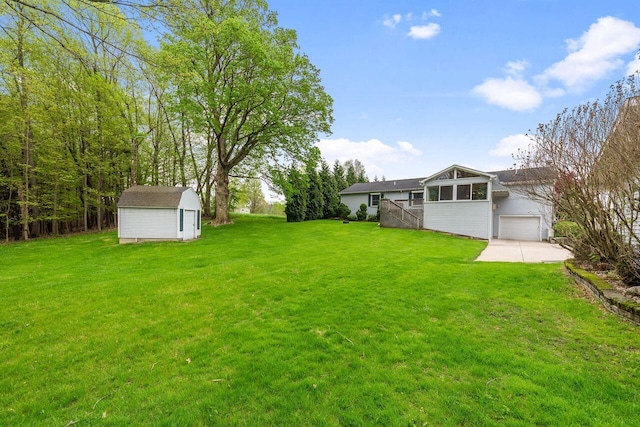 view of green lawn with a storage unit, a garage, and an outdoor structure