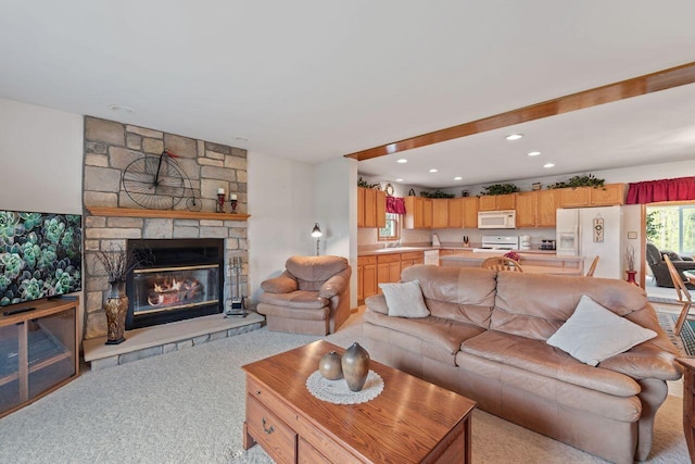 living area featuring a stone fireplace, light colored carpet, and recessed lighting