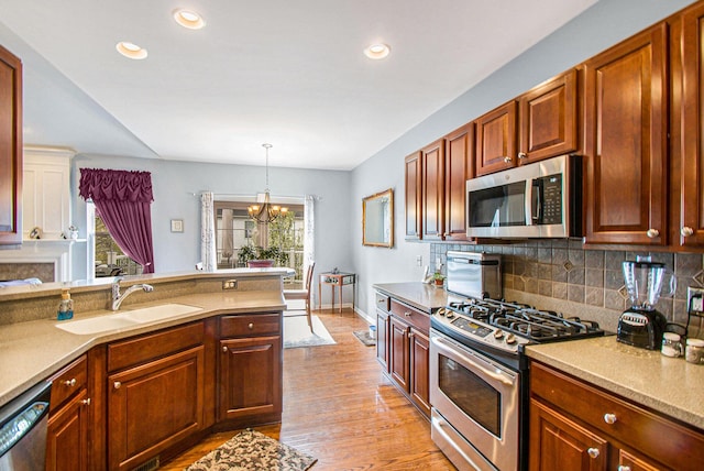 4261 Merriman Loop, Howell, MI 48843 - kitchen featuring stainless steel appliances, a sink, a chandelier, light wood-type flooring, and tasteful backsplash