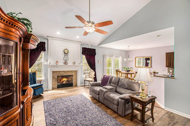 4261 Merriman Loop, Howell, MI 48843 - living area with vaulted ceiling, ceiling fan, healthy amount of natural light, light wood-style floors, and a tiled fireplace