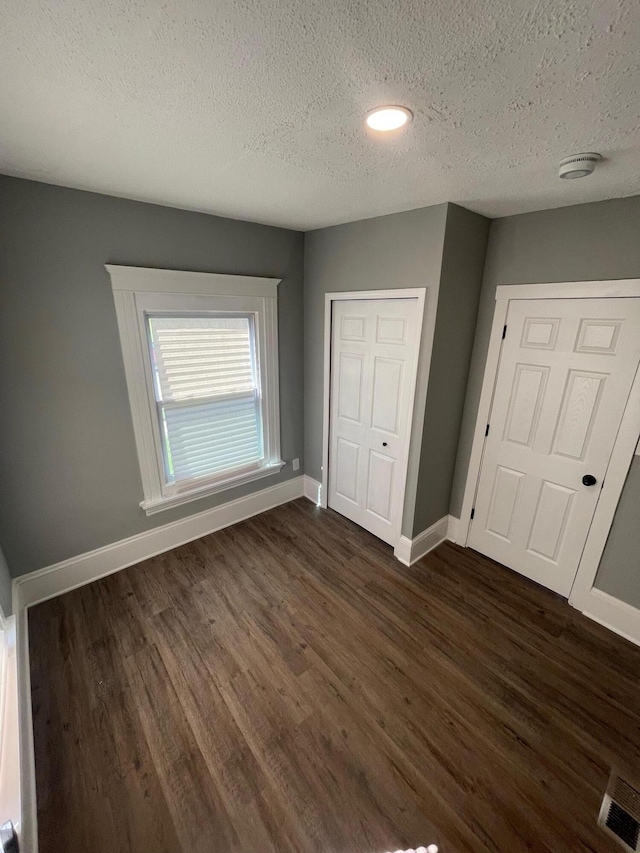 206 Mitchell St, Jackson, MI 49203 - unfurnished bedroom featuring a textured ceiling, dark wood-style flooring, baseboards, a closet, and recessed lighting