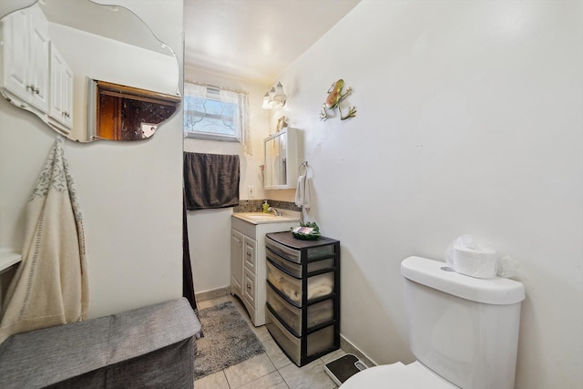 bathroom with toilet, tile patterned flooring, vanity, and baseboards