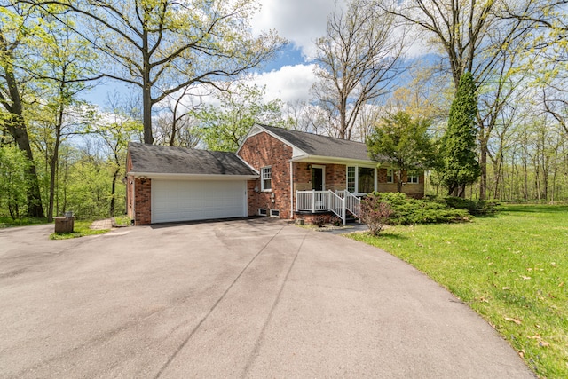 view of front of property with brick siding, asphalt driveway, an attached garage, a front lawn, and covered porch