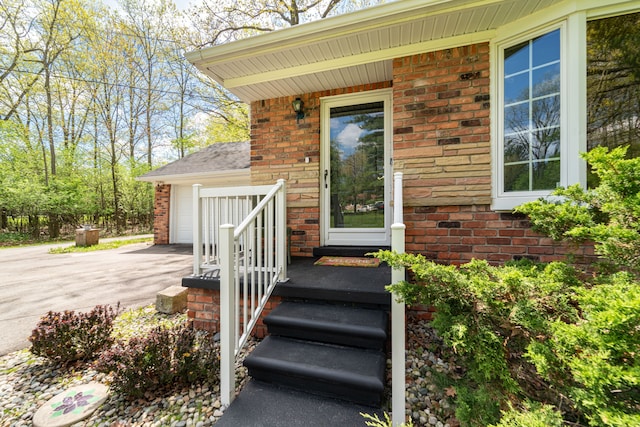 entrance to property featuring brick siding, driveway, a porch, and a garage