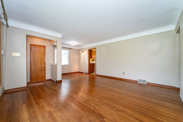 unfurnished living room featuring wood finished floors and baseboards