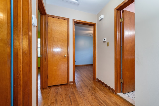 corridor with wood finished floors and baseboards