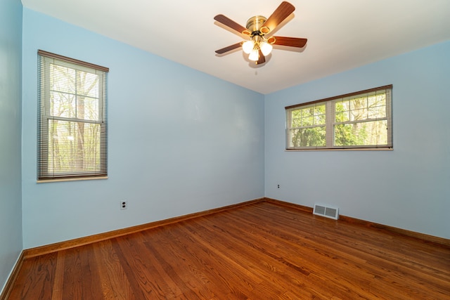 spare room featuring wood finished floors, baseboards, and ceiling fan