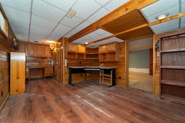 unfurnished office with wood walls and dark wood-type flooring
