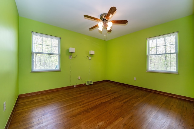 spare room with dark wood finished floors, a ceiling fan, and baseboards