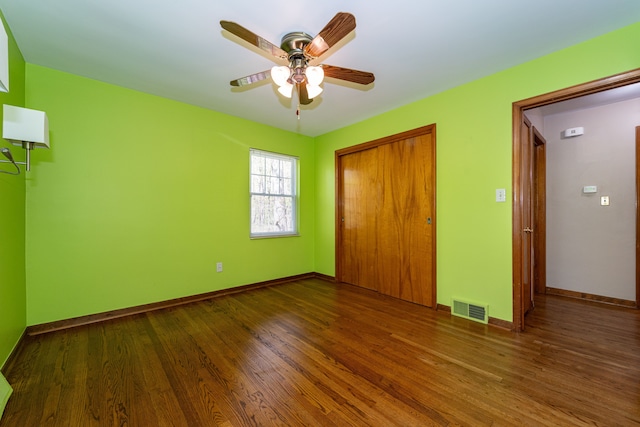 unfurnished bedroom featuring wood finished floors, a closet, baseboards, and a ceiling fan