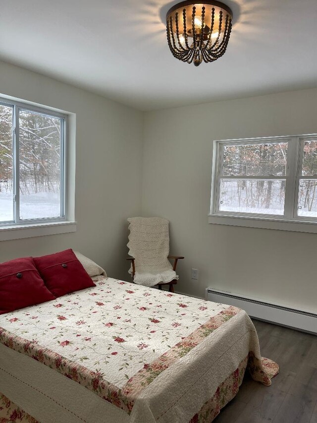 1192 Little Creek Rd SE, Alger, MI 48610 - bedroom with a baseboard radiator, wood finished floors, and a chandelier