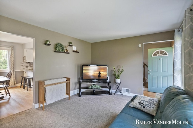 carpeted living room featuring baseboards and stairway