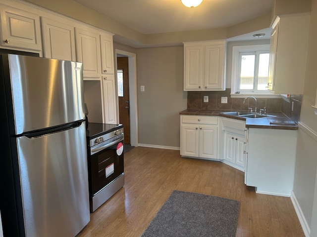 3608 W Webster Rd, Royal Oak, MI 48073 - kitchen with appliances with stainless steel finishes, a sink, white cabinets, tasteful backsplash, and light wood finished floors