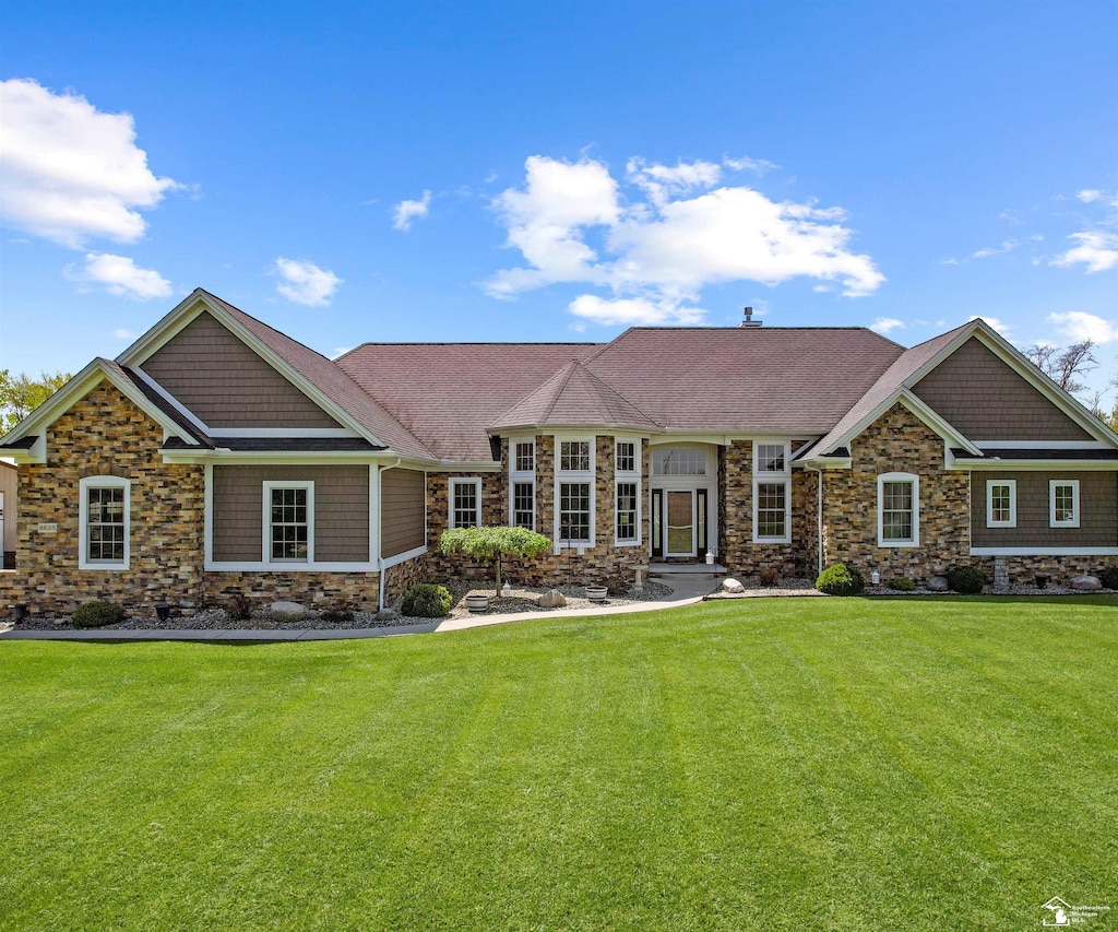 craftsman inspired home featuring stone siding, a front yard, and a shingled roof