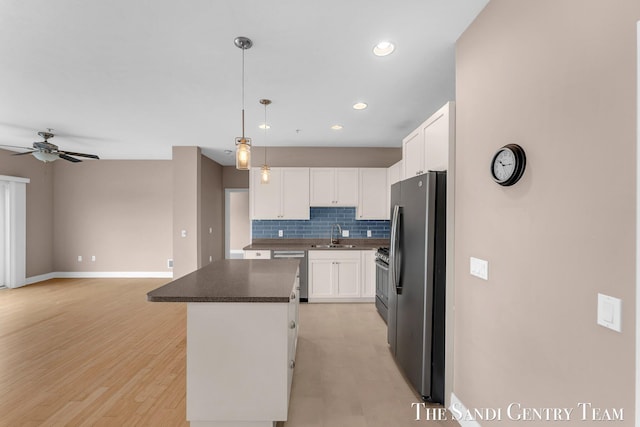 kitchen with stainless steel appliances, tasteful backsplash, white cabinetry, a kitchen island, and a sink