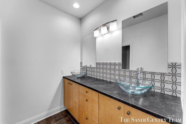 full bath featuring backsplash, double vanity, and baseboards