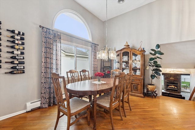 9669 Norman Rd, Clarkston, MI 48348 - dining room featuring a fireplace, wood finished floors, plenty of natural light, a chandelier, and a high ceiling