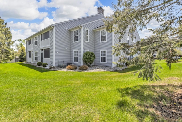 739 W Barrington Cir, Jackson, MI 49203 - back of house featuring a chimney, a yard, and central AC unit