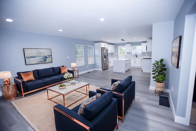 living room with recessed lighting, baseboards, and light wood-style floors