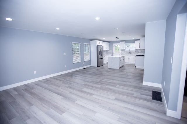 unfurnished living room with recessed lighting, baseboards, light wood-style floors, and a sink