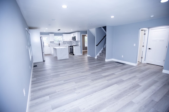 unfurnished living room featuring stairs, baseboards, recessed lighting, and light wood finished floors