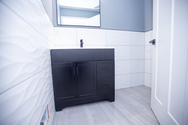 bathroom featuring vanity and tile walls