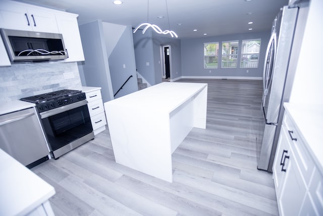kitchen featuring appliances with stainless steel finishes, a center island, recessed lighting, light countertops, and tasteful backsplash