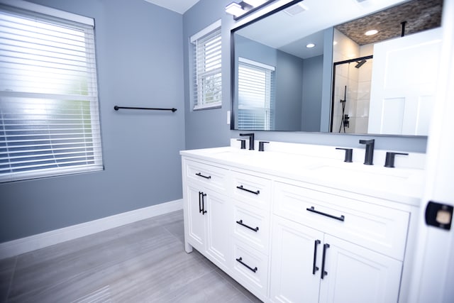 bathroom with a stall shower, double vanity, and baseboards