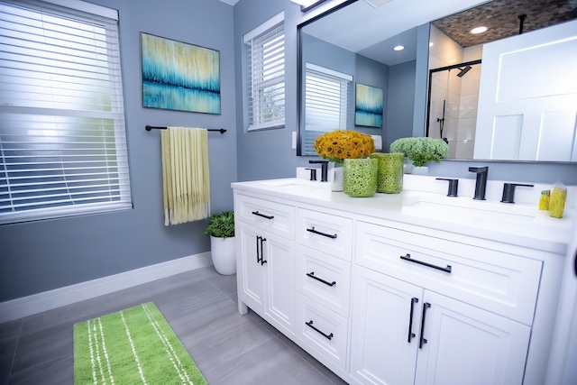full bath with a shower stall, double vanity, baseboards, and wood finished floors