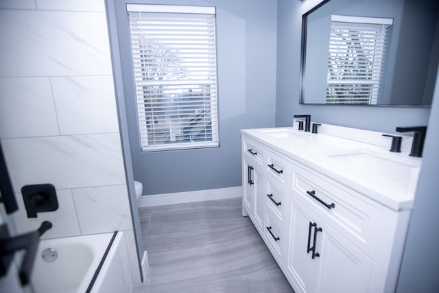 bathroom with double vanity, baseboards, and bathtub / shower combination