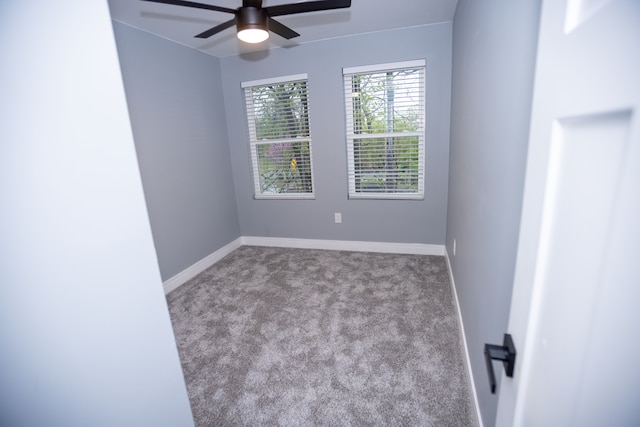carpeted spare room featuring ceiling fan and baseboards