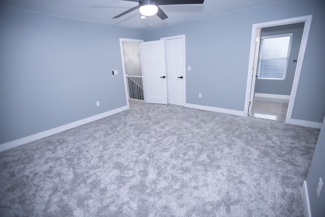 unfurnished bedroom featuring carpet, baseboards, ensuite bath, ceiling fan, and a closet