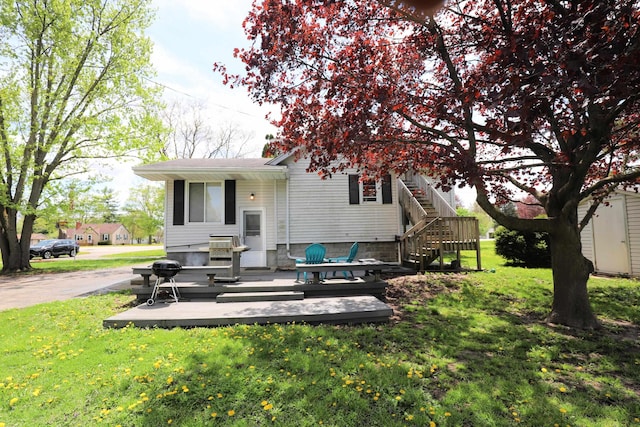 rear view of property with a deck, a lawn, a storage unit, and an outbuilding