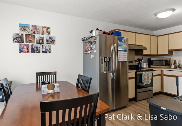 kitchen featuring appliances with stainless steel finishes, under cabinet range hood, cream cabinets, and light wood-type flooring