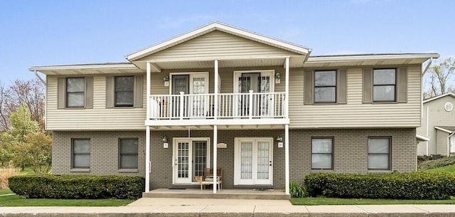 multi unit property featuring a balcony, brick siding, and covered porch