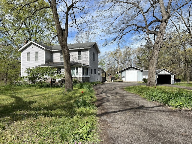 view of front of house with a chimney, a garage, and an outbuilding