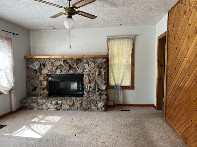 unfurnished living room featuring a fireplace, a ceiling fan, carpet, plenty of natural light, and a textured ceiling