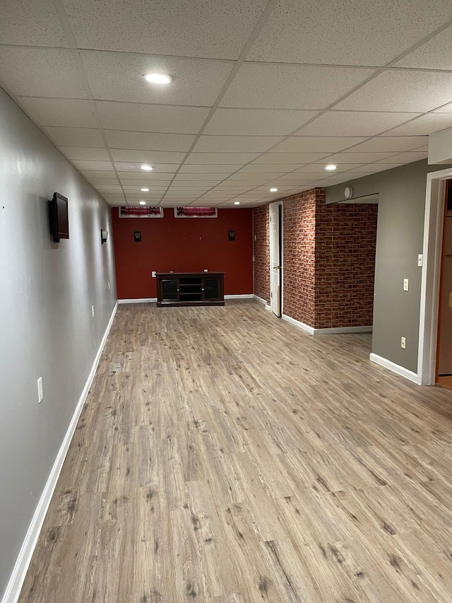 25432 Wexford Ave, Warren, MI 48091 - unfurnished living room featuring a drop ceiling, wood finished floors, baseboards, brick wall, and recessed lighting