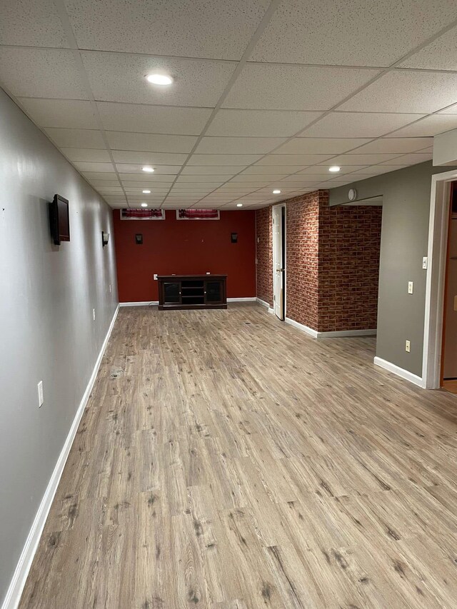 25432 Wexford Ave, Warren, MI 48091 - unfurnished living room featuring a paneled ceiling, wood finished floors, baseboards, brick wall, and recessed lighting