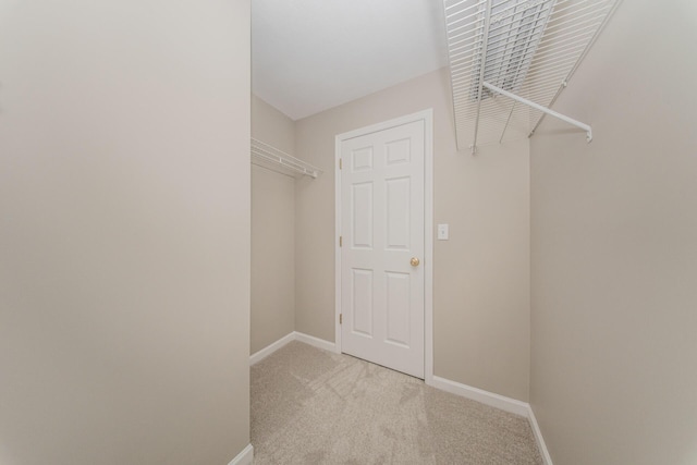 walk in closet with light carpet
