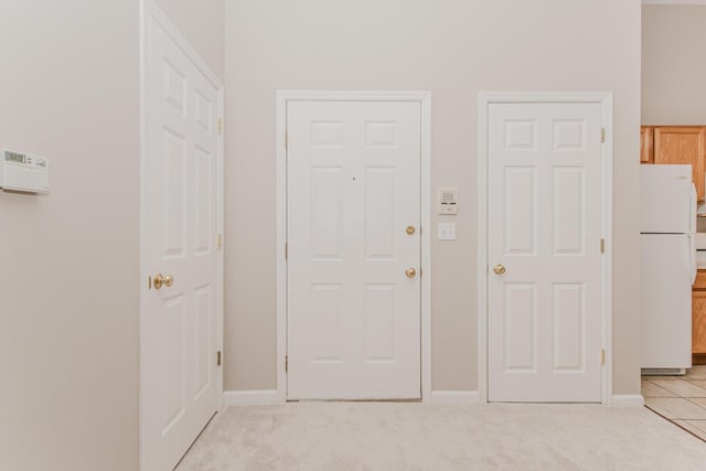 foyer featuring light carpet and baseboards