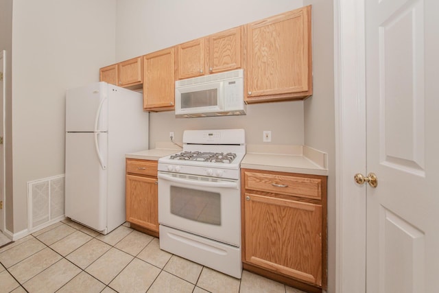 kitchen with white appliances, light brown cabinetry, light countertops, and light tile patterned floors