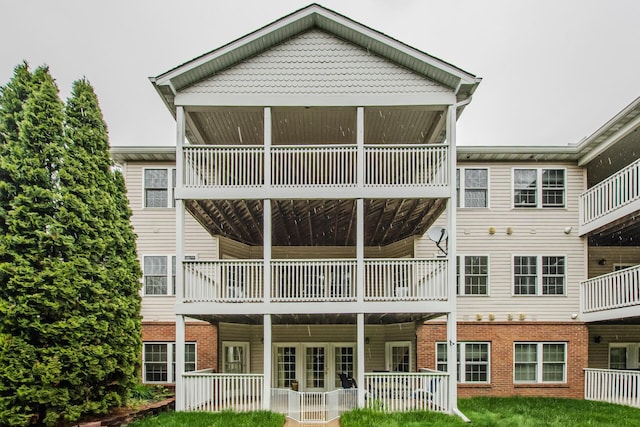 back of house featuring brick siding and a balcony